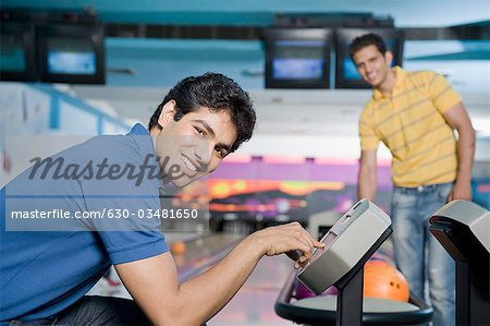 Jeune homme de fonctionnement du panneau de commande et son ami lui en regardant dans un bowling