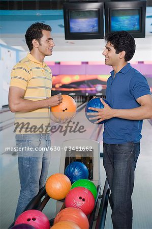 Zwei junge Männer in eine Bowlingbahn Bowling-Kugeln halten