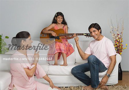 Fille jouant de la guitare avec ses parents