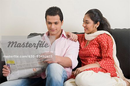 Couple reading a newspaper on a couch