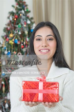 Frau hält ein Weihnachtsfest vorhanden und lächelnd