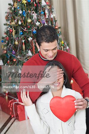 Man covering his wife's eyes to give a present