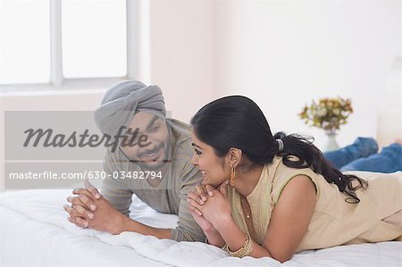 Paar auf dem Bett liegend und Lächeln