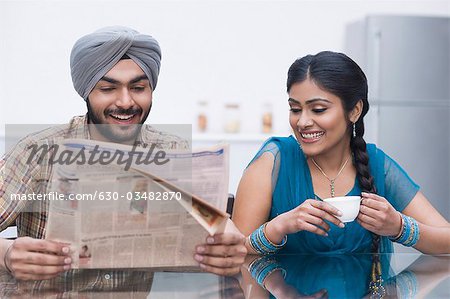 Couple reading a newspaper and smiling