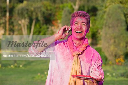 Man celebrating Holi and using a mobile phone