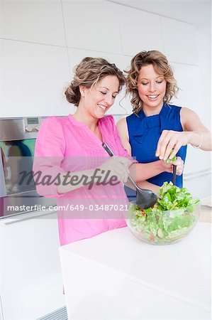 Two women preparing green salad together