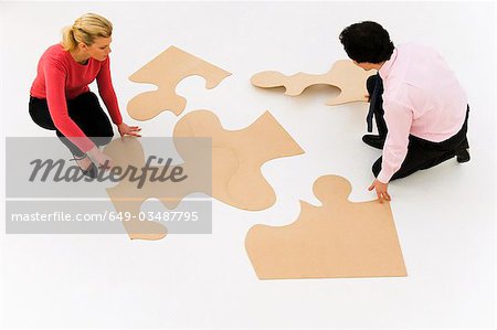 Business people work at finishing puzzle Business people work at finishing puzzle