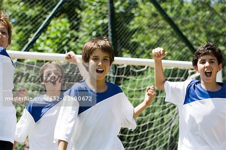 Boys on soccer field, fists raised in victory