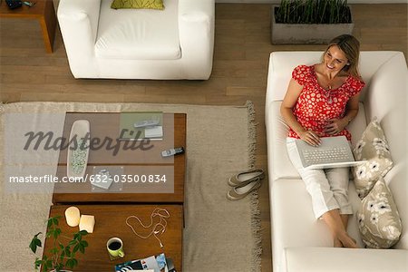 Woman relaxing in living room using laptop computer