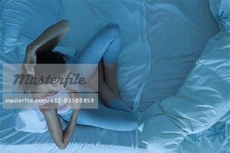 Femme assise dans son lit en prenant la température