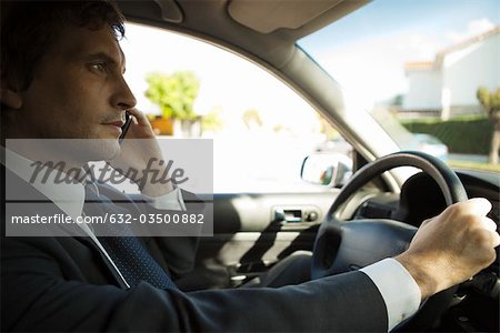 Homme d'affaires utilisant un téléphone cellulaire pendant la conduite