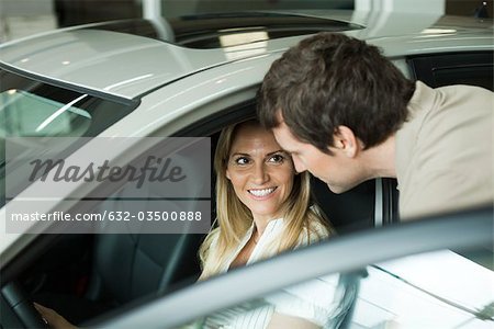 Couple vérifiant des voitures neuves dans la salle d'exposition du concessionnaire