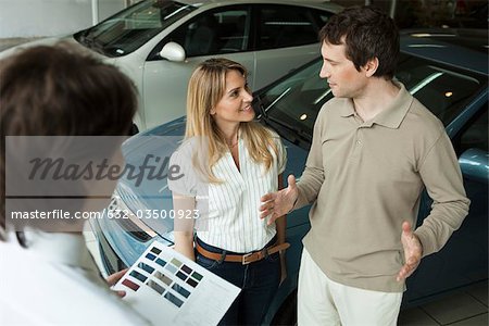 Paar im Autohaus Autohaus diskutieren neue Pkw-Optionen mit Verkäufer