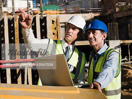 Mature men with laptop on construction site