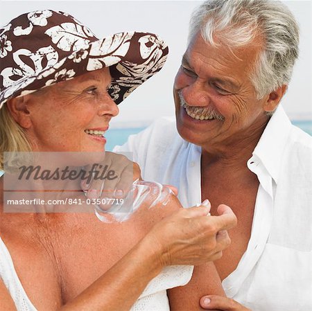 Altes Paar am Strand, Anwendung von Sonnencreme auf Frau Mann