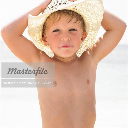 Junge (6-8) am Strand tragen Stroh Hut