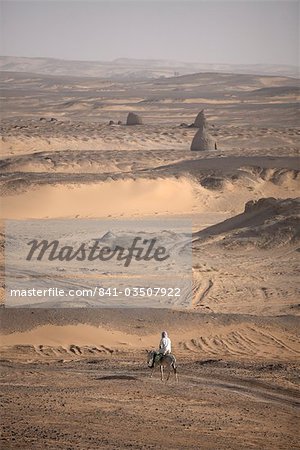 Un homme sur le dos de mulet traverse le désert autour de l'antique ville de Old Dongola, Soudan, Afrique