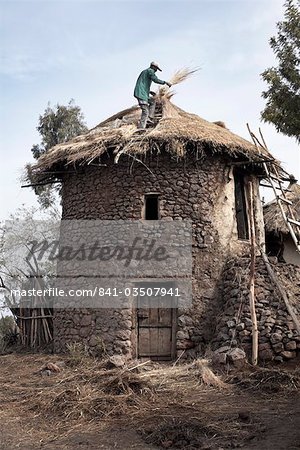 Un homme thatches le toit de sa maison dans la ville de Lalibela, Ethiopie, Afrique