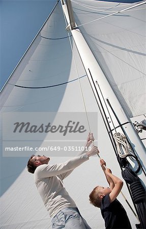 Father and son pulling rope on yacht