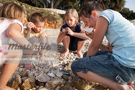 Enfants à l'écoute de coquillages sur la plage