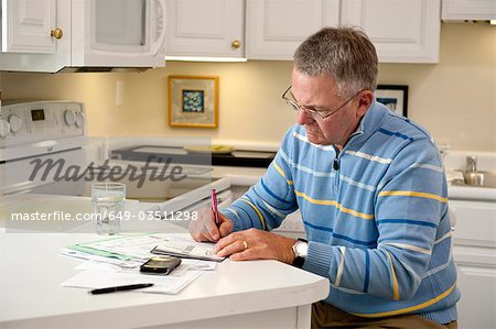 Mature man paying bills in kitchen