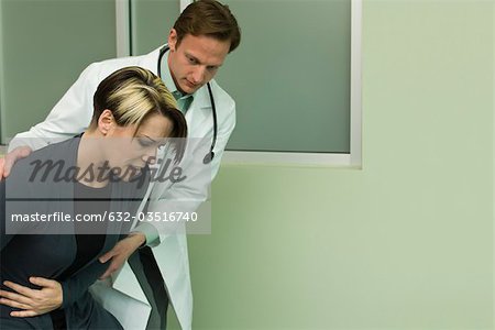 Doctor assisting patient experiencing severe abdominal pain