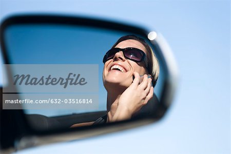Woman talking on cell phone, reflection in side-view mirror
