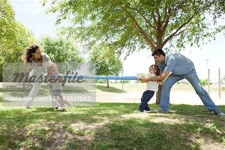 Family playing tug-of-war in park