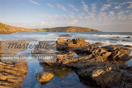 Evening sunlight bathes the rocky shores and cliffs golden at Wembury Bay in South Devon, England, United Kingdom, Europe