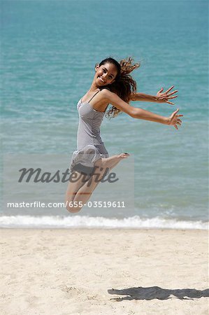 happy young woman jumping in air at the beach