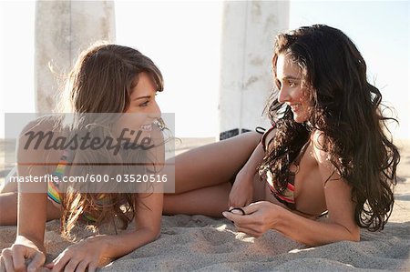 Jeunes femmes avec planches couché sur la plage, Zuma Beach, Californie, USA
