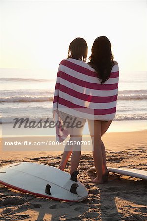 Backview of Young Women with Surfboards, Standing on Beach watching Sunset, Zuma Beach, California, USA