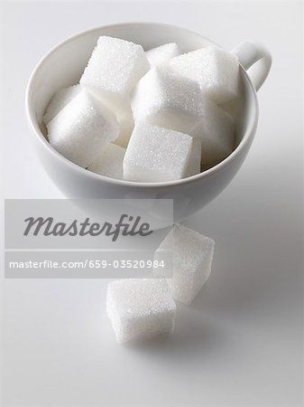 Sugar cubes in and beside white cup