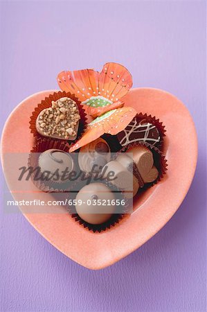 Chocolates in heart-shaped dish (coloured background)