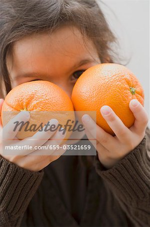 Girl holding two oranges in front of her face