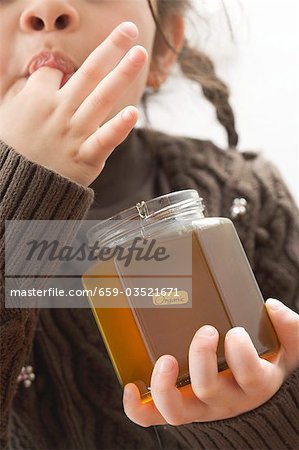 Girl tasting organic honey out of the jar