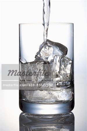 Versez l'eau dans un verre contenant des cubes de glace