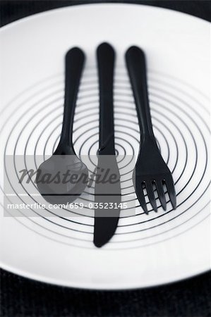 Black plastic cutlery on a plate
