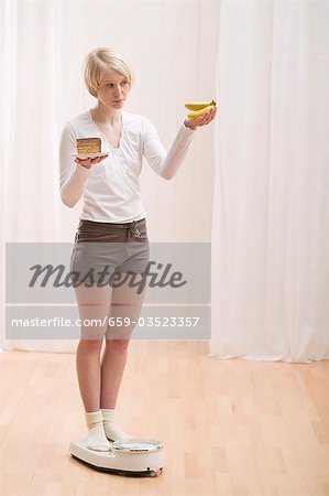 Jeune femme avec un morceau de gâteau et de bananes sur les échelles