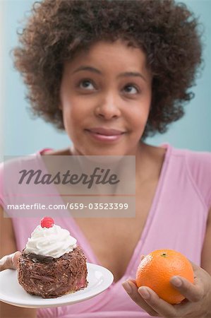 Jeune femme indécise entre le gâteau et orange