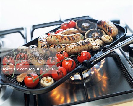 Sausages, mushrooms and tomatoes in a grill frying pan