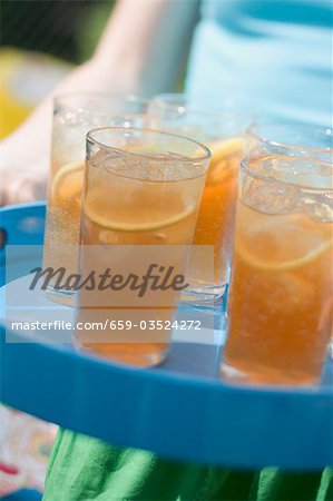 Person serving several glasses of iced tea on a tray