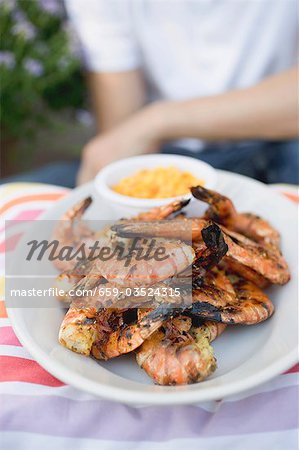 Grilled shrimps on plate, man in background Grilled shrimps on plate, man in background