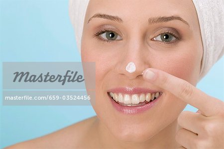 Femme tamponnant crème pour le visage sur son nez