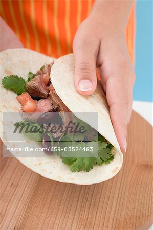 Main pliage tortilla sur le bœuf de remplissage