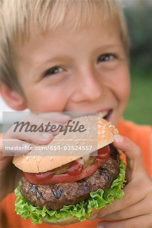 Small boy eating hamburger