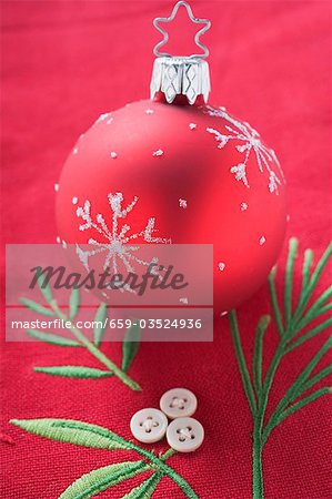 Red Christmas tree bauble on embroidered linen cloth