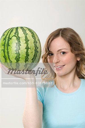 Frau hält Wassermelone auf der einen Seite