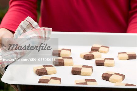 Person holding baking tray of checkerboard cookies