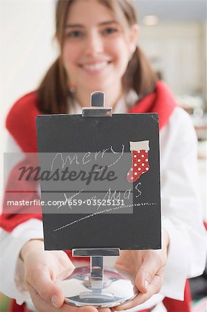 Young woman holding slate with the words Merry X-mas (for table)